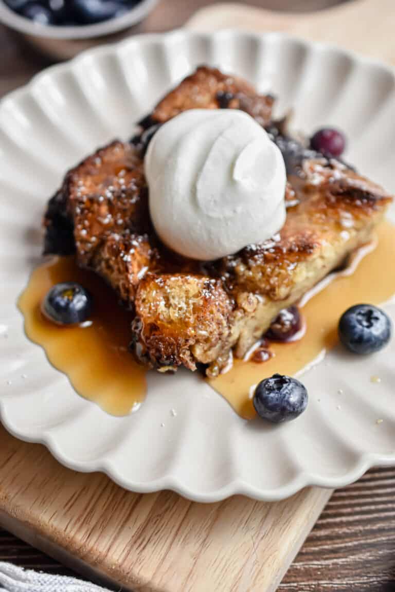 A portion of the french toast blueberry casserole is on a fluted plate.
