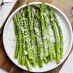 A plate of Instant Pot Asparagus are on a white plate on a cutting board.