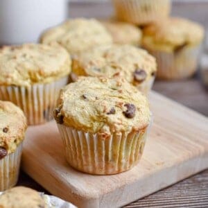 A 2 ingredient banana muffin is on a cutting board with more muffins in the background.