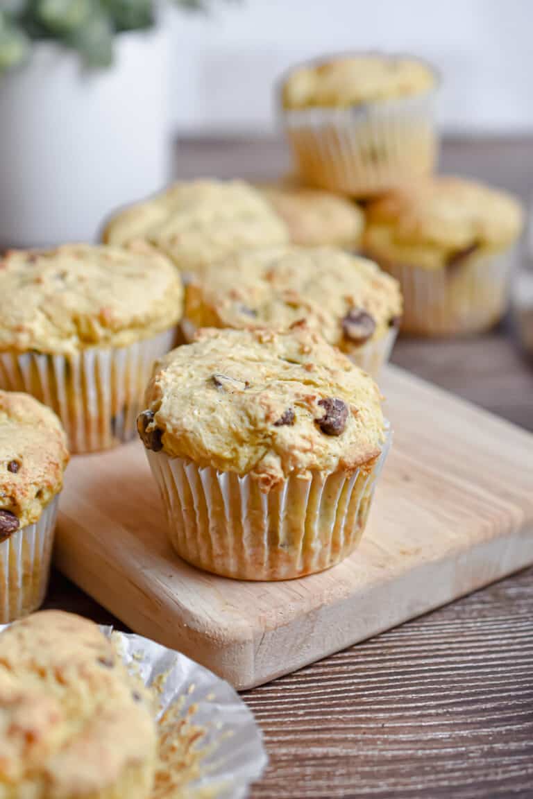 A 2 ingredient banana muffin is on a cutting board with more muffins in the background.