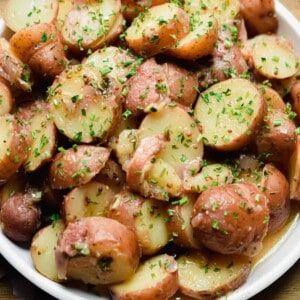 A plate of Instant Pot German Potato Salad is on a cutting board.