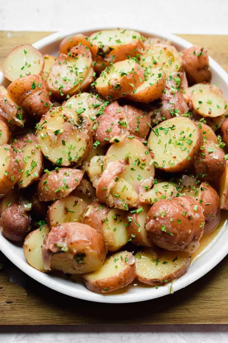 A plate of Instant Pot German Potato Salad is on a cutting board.