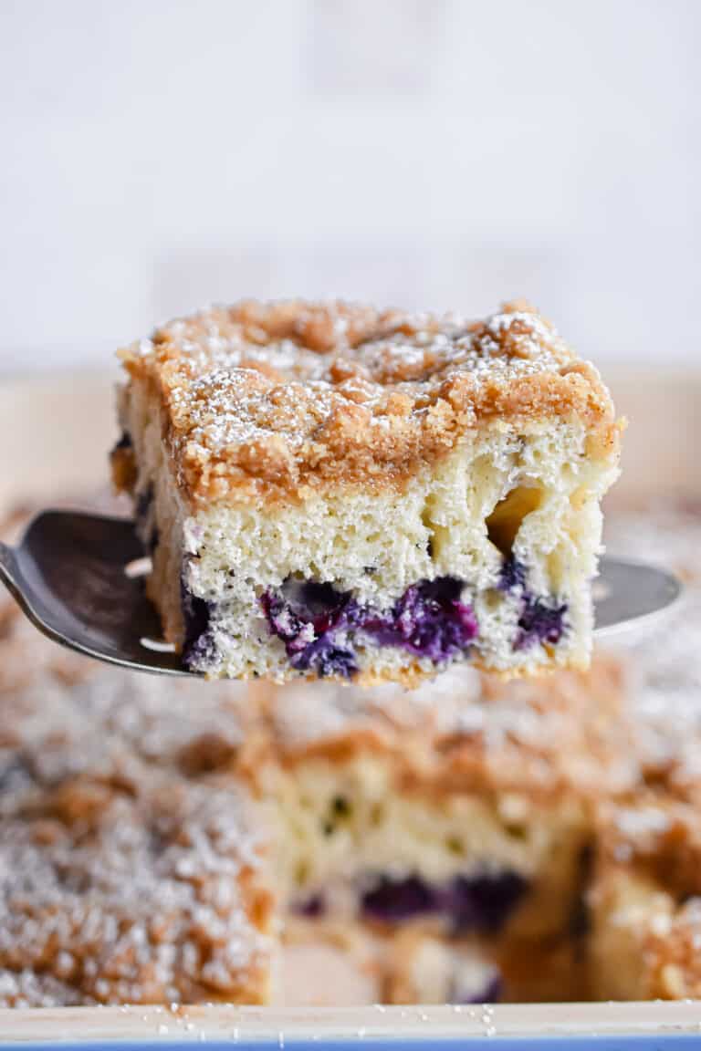 A pie knife is holding a piece of the bisquick blueberry coffee cake.
