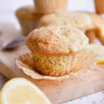 A sourdough lemon poppy seed muffin is on a cutting board, unwrapped.