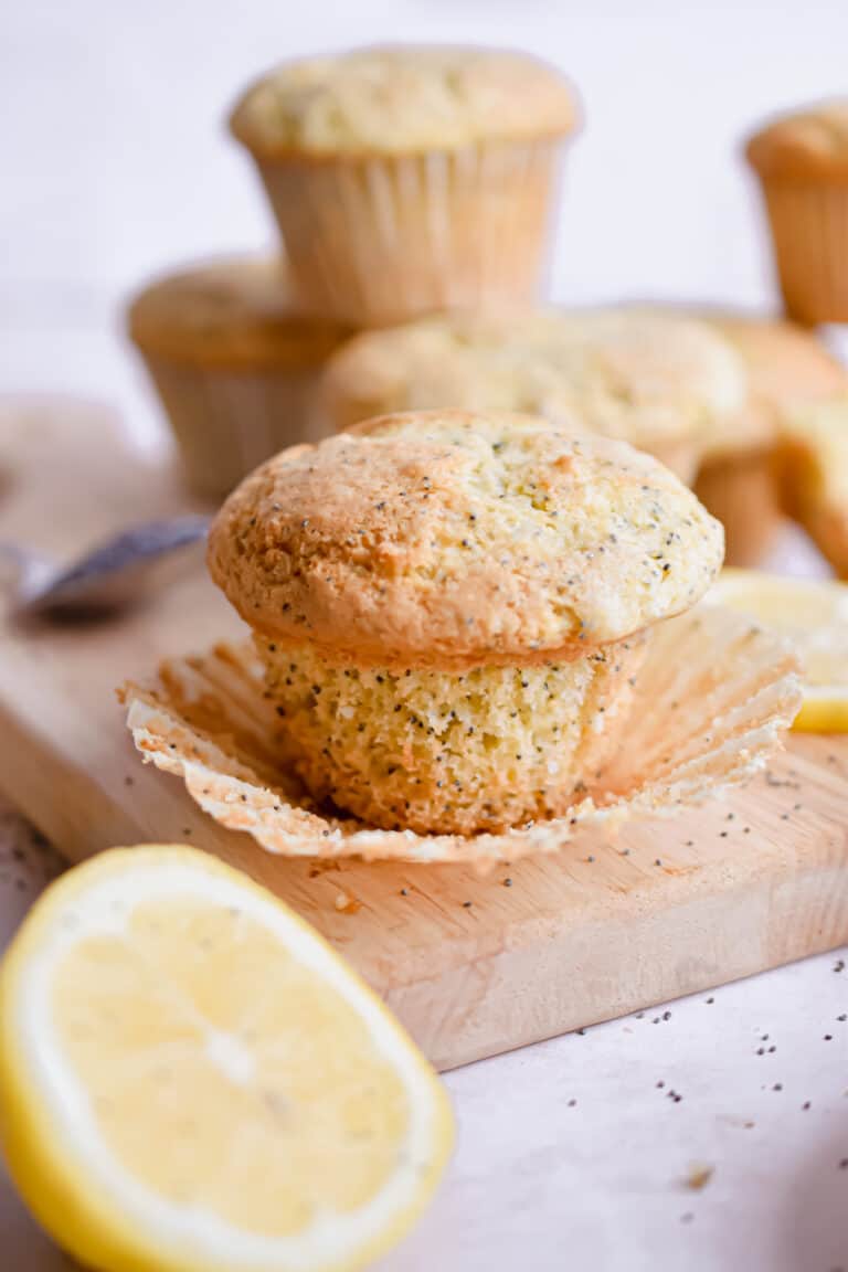 A sourdough lemon poppy seed muffin is on a cutting board, unwrapped.
