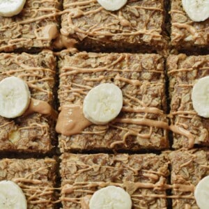 Nine 3 ingredient banana oatmeal bars are topped with a slice of banana.