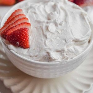 The 3 ingredient strawberry fluff dip is in a large bowl with strawberries surrounding it.
