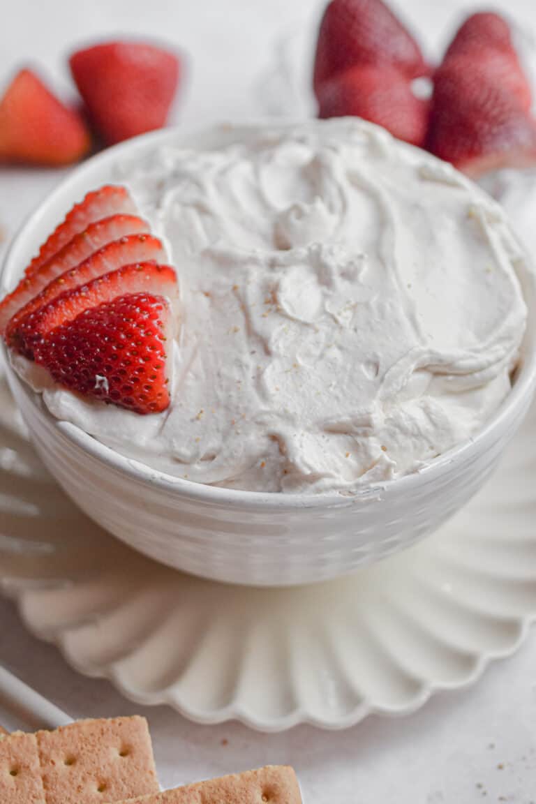 The 3 ingredient strawberry fluff dip is in a large bowl with strawberries surrounding it.