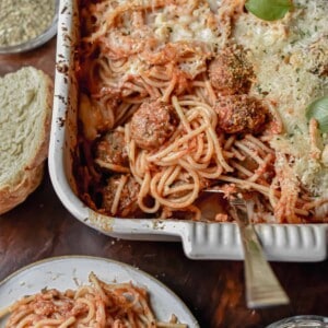 A fork is in the baking dish with the baked spaghetti and meatballs.