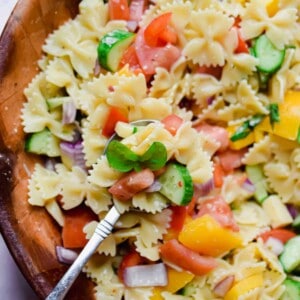 A spoon is holding some of the bowtie pasta salad with Italian dressing