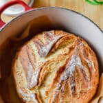 The sourdough discard bread is in a Dutch oven on a cutting board.