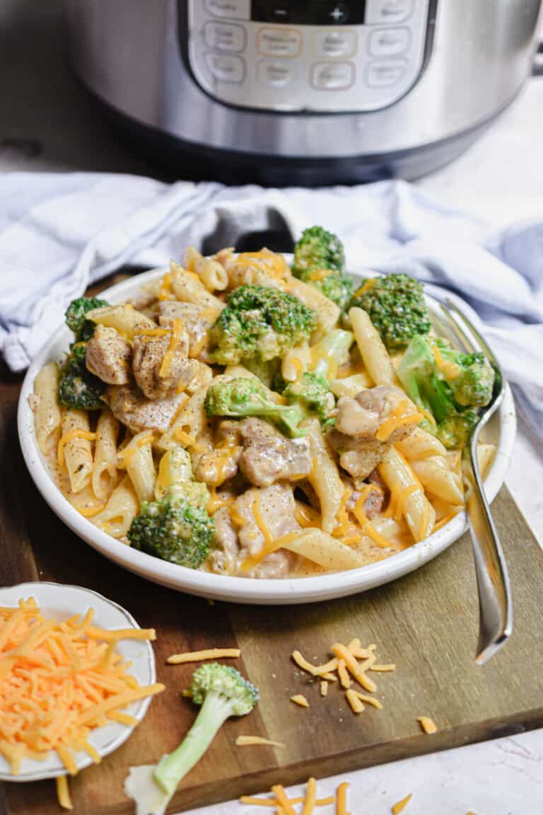 The Instant Pot Chicken Broccoli Pasta is on a plate on a cutting board.