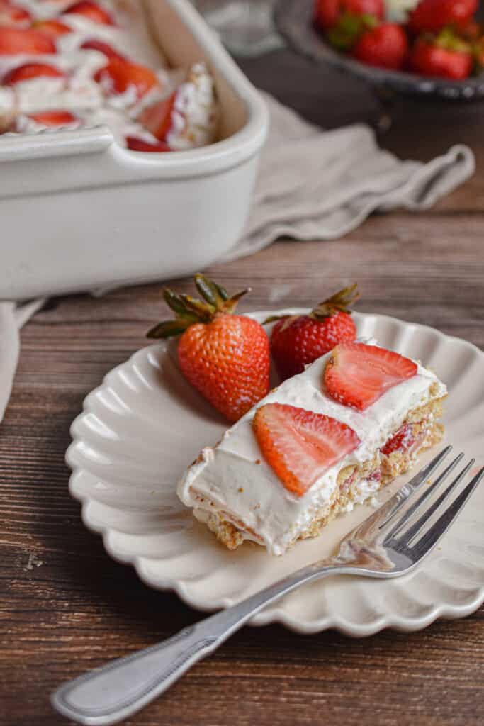 A slice of the strawberry icebox cake is on a fluted plate.