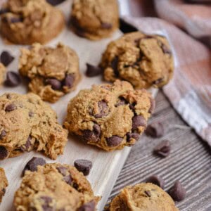 3 ingredient pumpkin cookies are on a cutting board with an orange kitchen towel in the background.