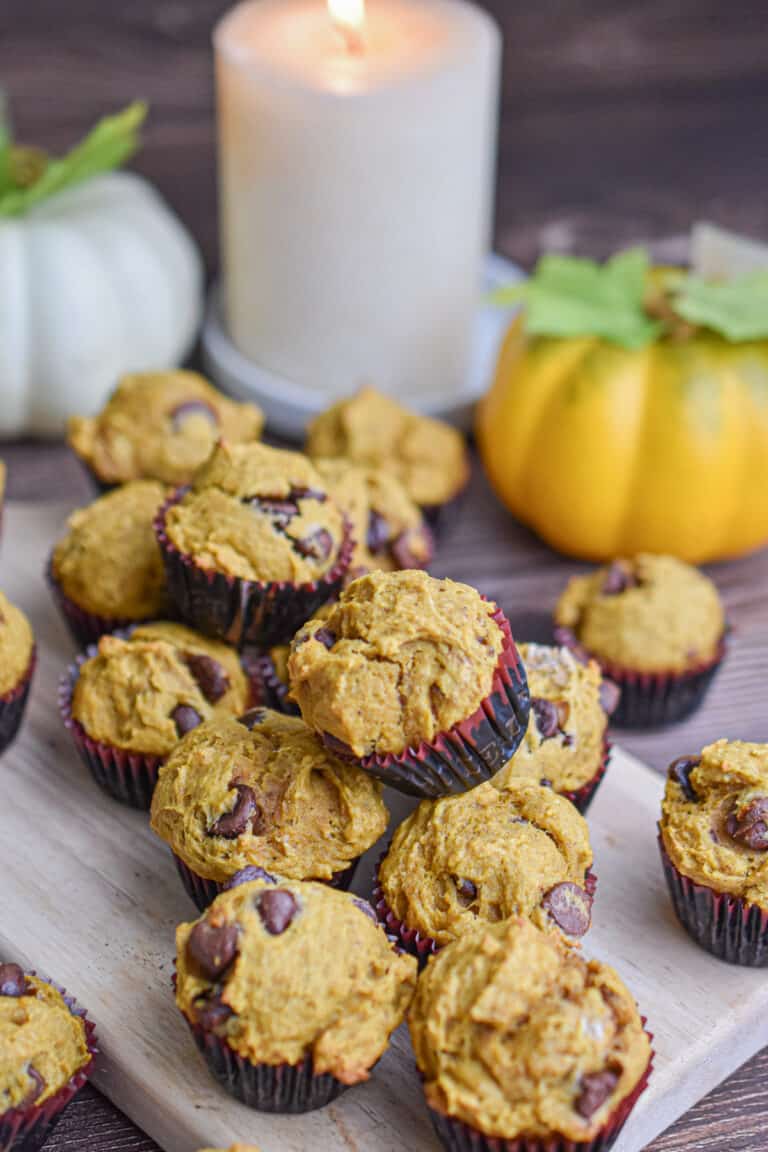 The mini pumpkin muffins are piled on a cutting board.