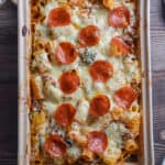 The pizza casserole is in a baking dish on a wooden background.