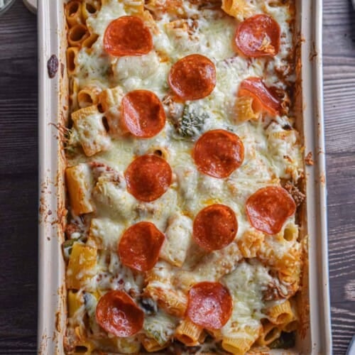 The pizza casserole is in a baking dish on a wooden background.