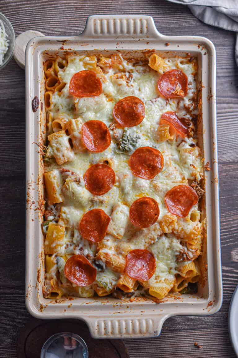 The pizza casserole is in a baking dish on a wooden background.