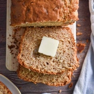 A pat of butter is on a slice of the banana bread with pancake mix.