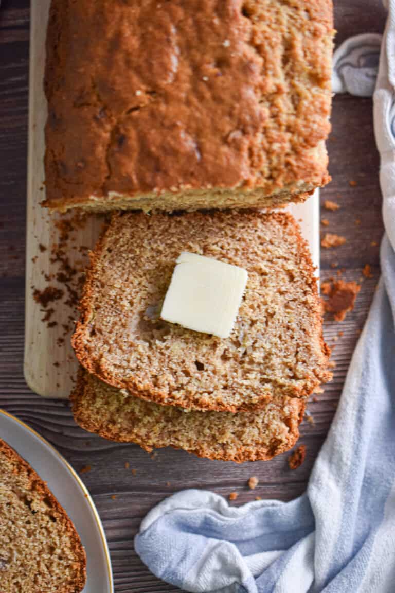 A pat of butter is on a slice of the banana bread with pancake mix.
