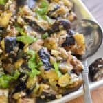 The Italian sauteed eggplant is on a square plate with a spoon on the plate.