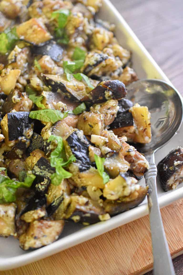 The Italian sauteed eggplant is on a square plate with a spoon on the plate.