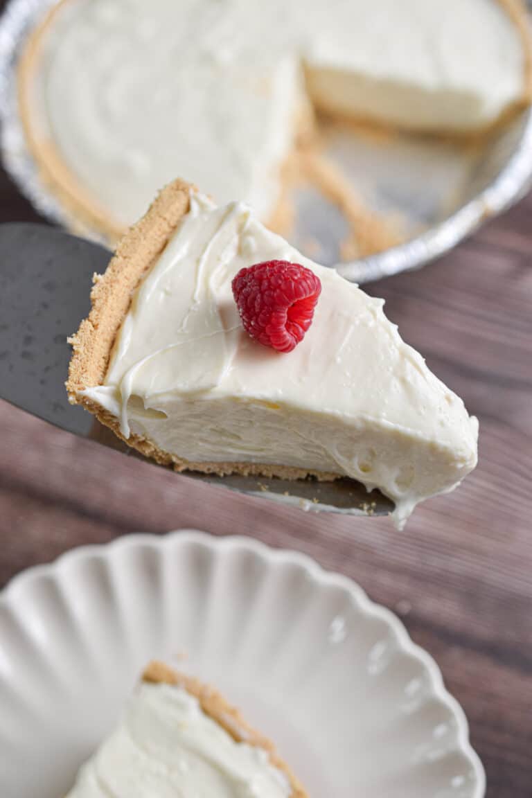 A pie holder is holding a 3-ingredient no bake cheesecake slice.