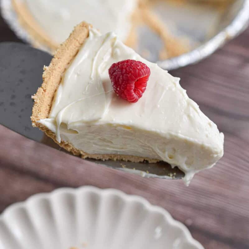A pie holder is holding a 3-ingredient no bake cheesecake slice.