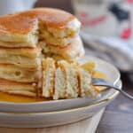 A fork is holding a piece of the stack of Bisquick pancakes no eggs.