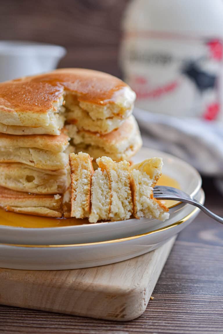 A fork is holding a piece of the stack of Bisquick pancakes no eggs.
