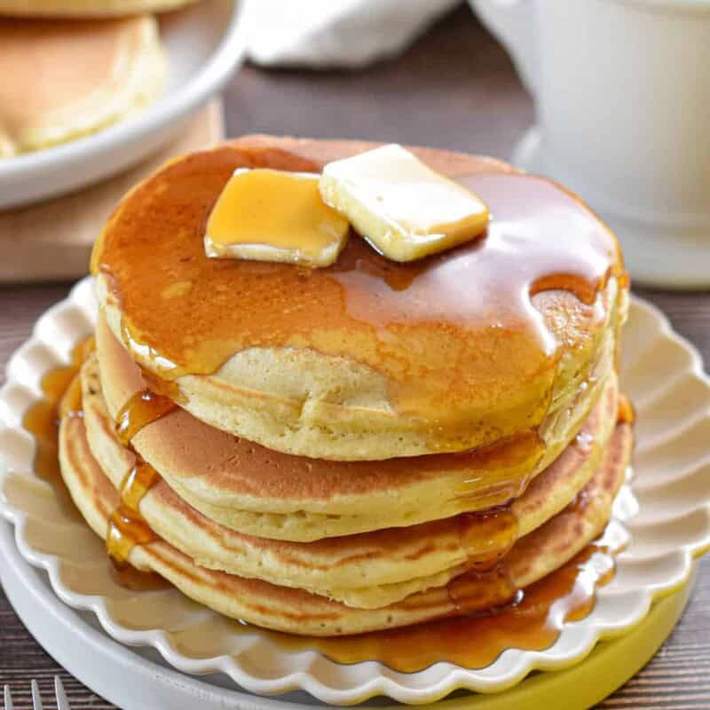 Maple syrup is poured and pooled on a stack of Bisquick pancakes.