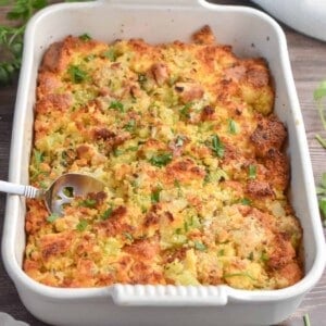 A spoon is in the casserole dish ready to serve the cornbread dressing with jiffy mix.