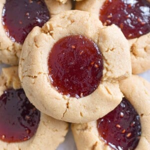 A pile of peanut butter and jam thumbprint cookies is shown.