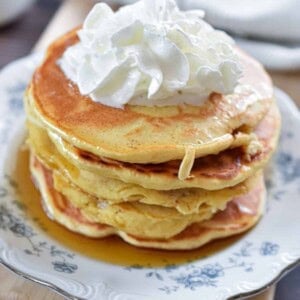 Whipped cream is on top of a stack of Bisquick pancakes for one.