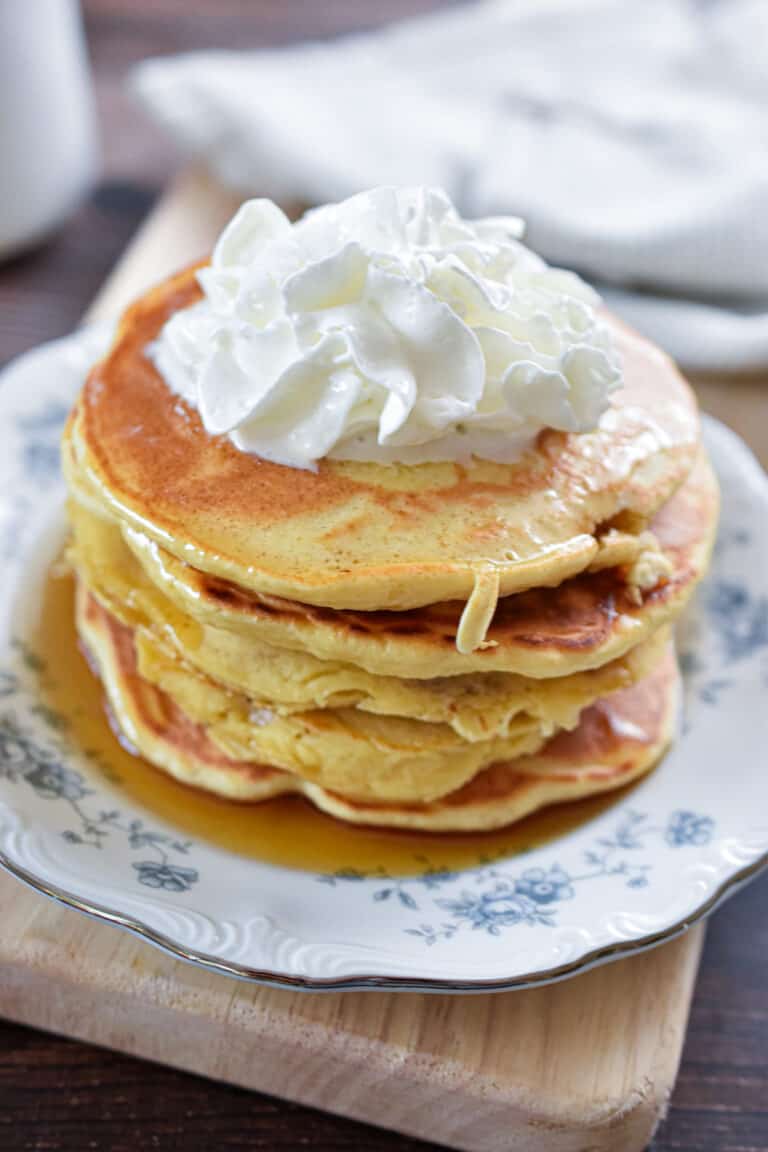 Whipped cream is on top of a stack of Bisquick pancakes for one.