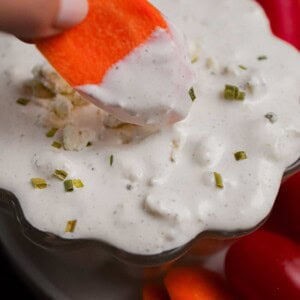 A carrot is being dipped into the blue cheese dip.