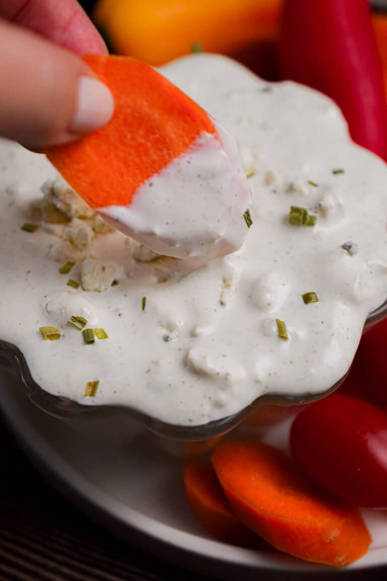 A carrot is being dipped into the blue cheese dip.