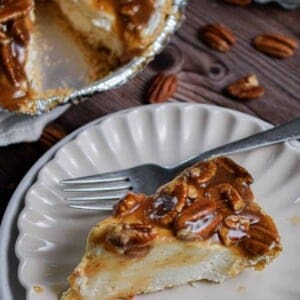 A slice of no bake pecan pie cheesecake is on a fluted plate.