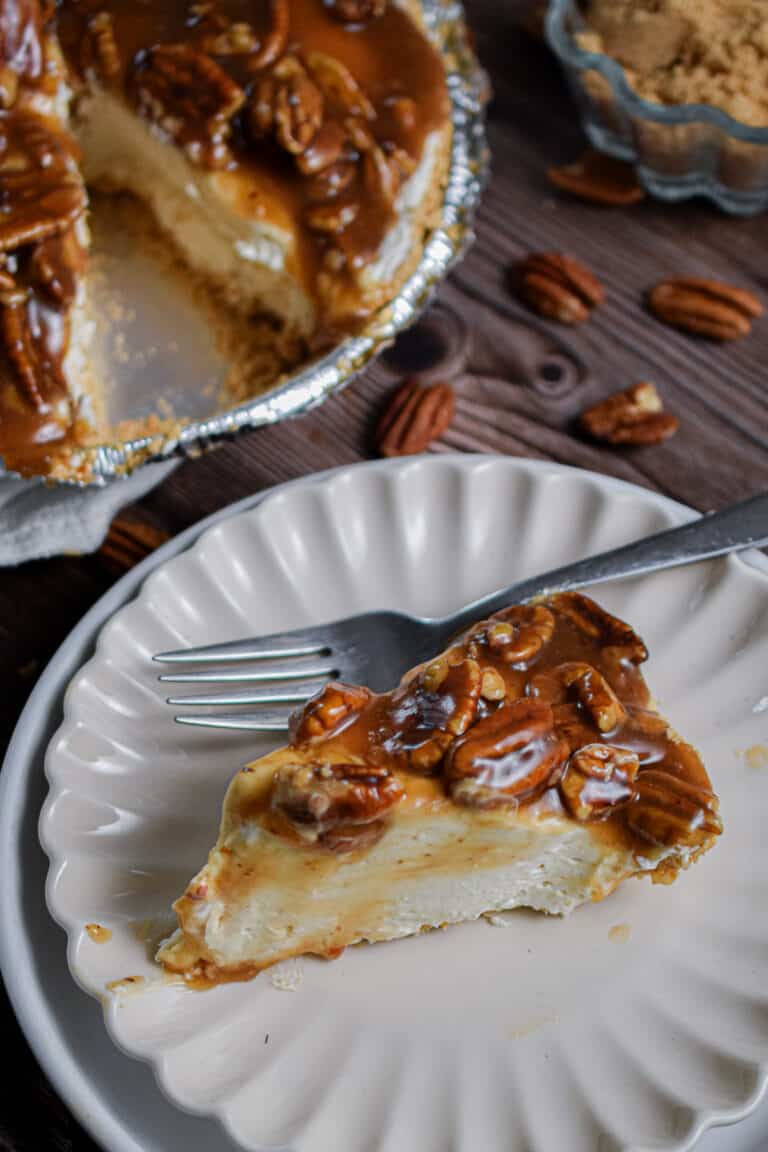 A slice of no bake pecan pie cheesecake is on a fluted plate.