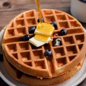 Maple syrup is being poured onto the stack of Bisquick waffles.