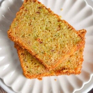 Two slices of zucchini bread with self rising flour are on a fluted plate.