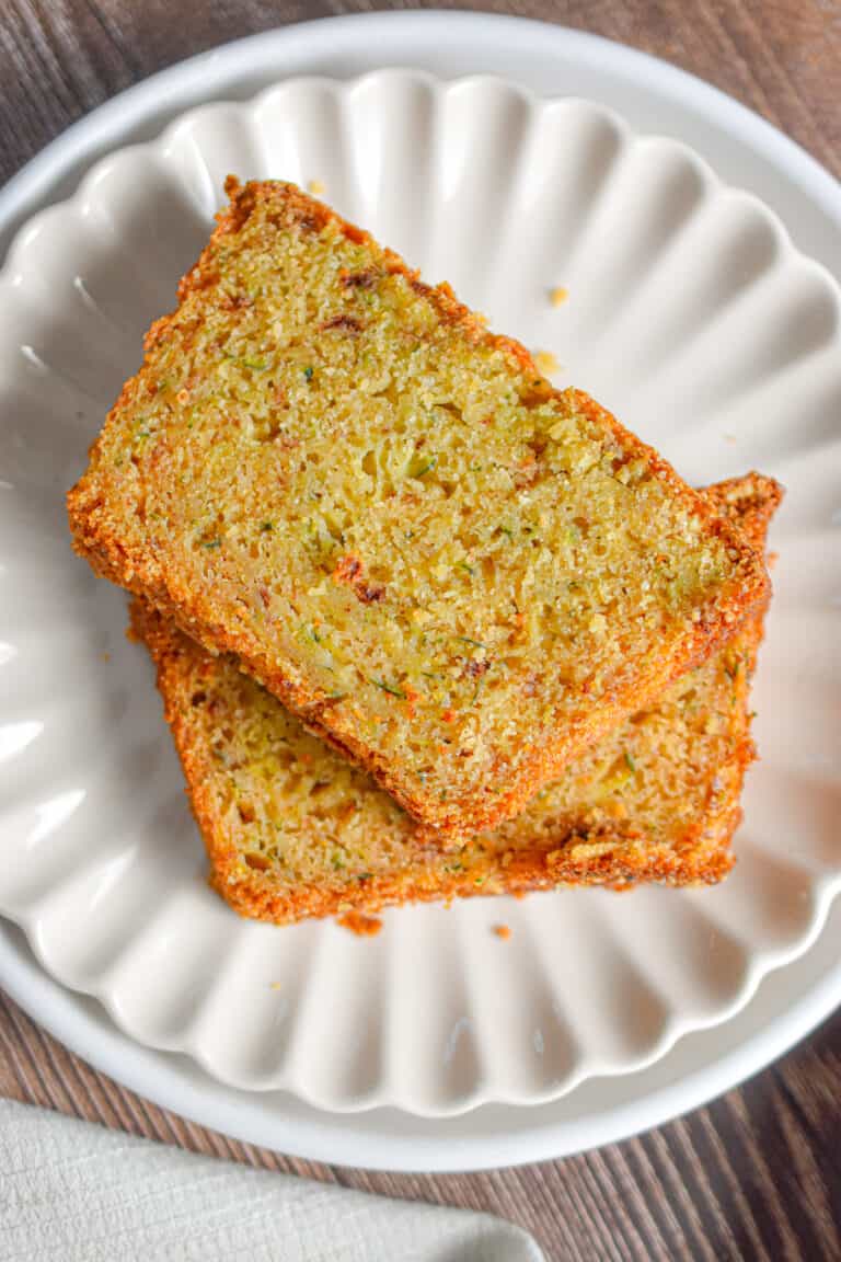 Two slices of zucchini bread with self rising flour are on a fluted plate.