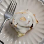 A cinnamon roll with self rising flour is on a fluted plate with a fork.
