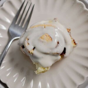 A cinnamon roll with self rising flour is on a fluted plate with a fork.