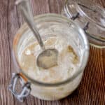 The ingredients for how to make a sourdough starter is in a glass jar.