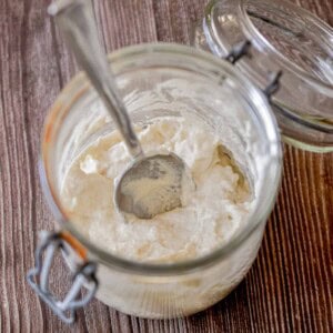 The ingredients for how to make a sourdough starter is in a glass jar.