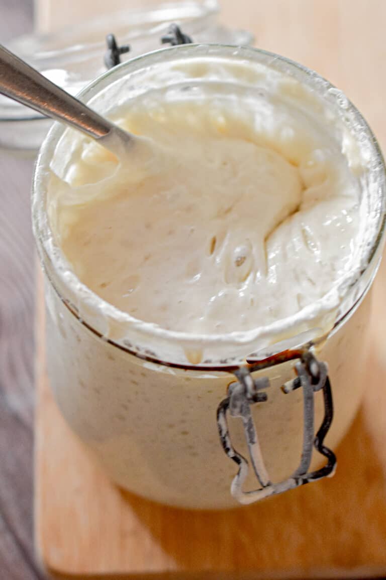 A spoon is in the jar of the new sourdough starter.