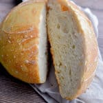 The same day sourdough bread is on a tan napkin cut in half.