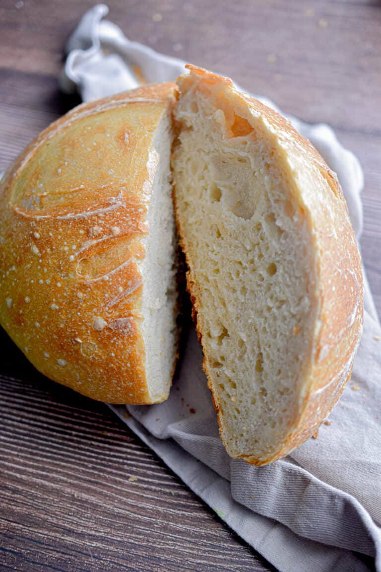 The same day sourdough bread is on a tan napkin cut in half.