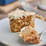A piece of the sourdough discard carrot cake has a fork piece taken out of it.